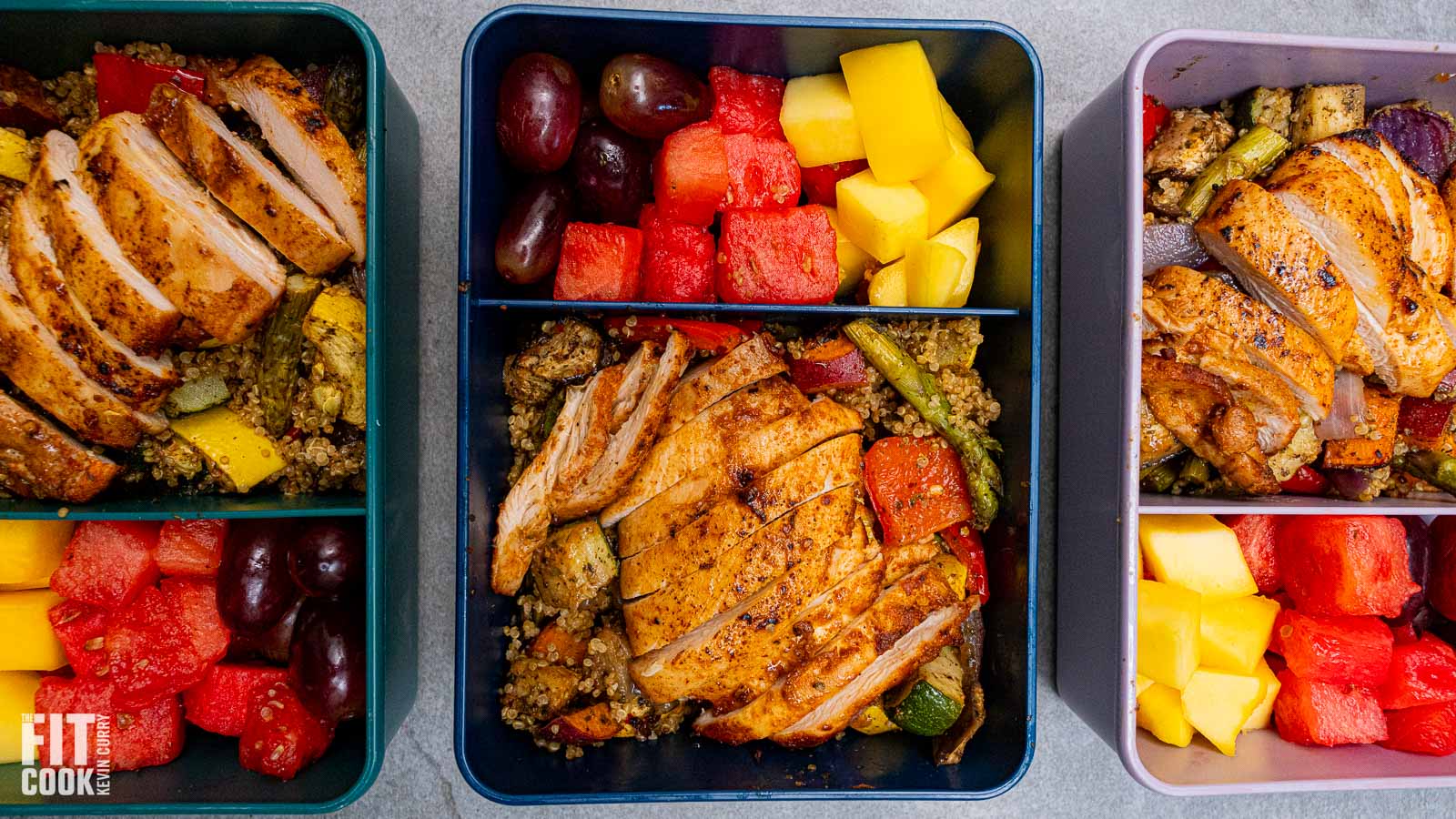 A high-protein meal prep container featuring sliced sriracha chicken over a bed of quinoa with roasted vegetables and a side of fresh fruit.