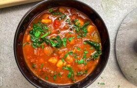 Harissa chickpea stew simmering in a pot with a cinnamon stick and bay leaf