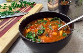 Harissa chickpea stew with dino kale in a bowl, cinnamon stick on the side