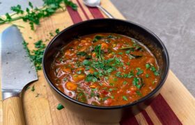 Harissa chickpea stew with dino kale in a bowl, cinnamon stick on the side