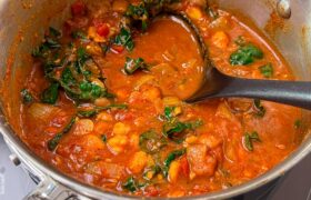 Harissa chickpea stew simmering in a pot with a cinnamon stick and bay leaf
